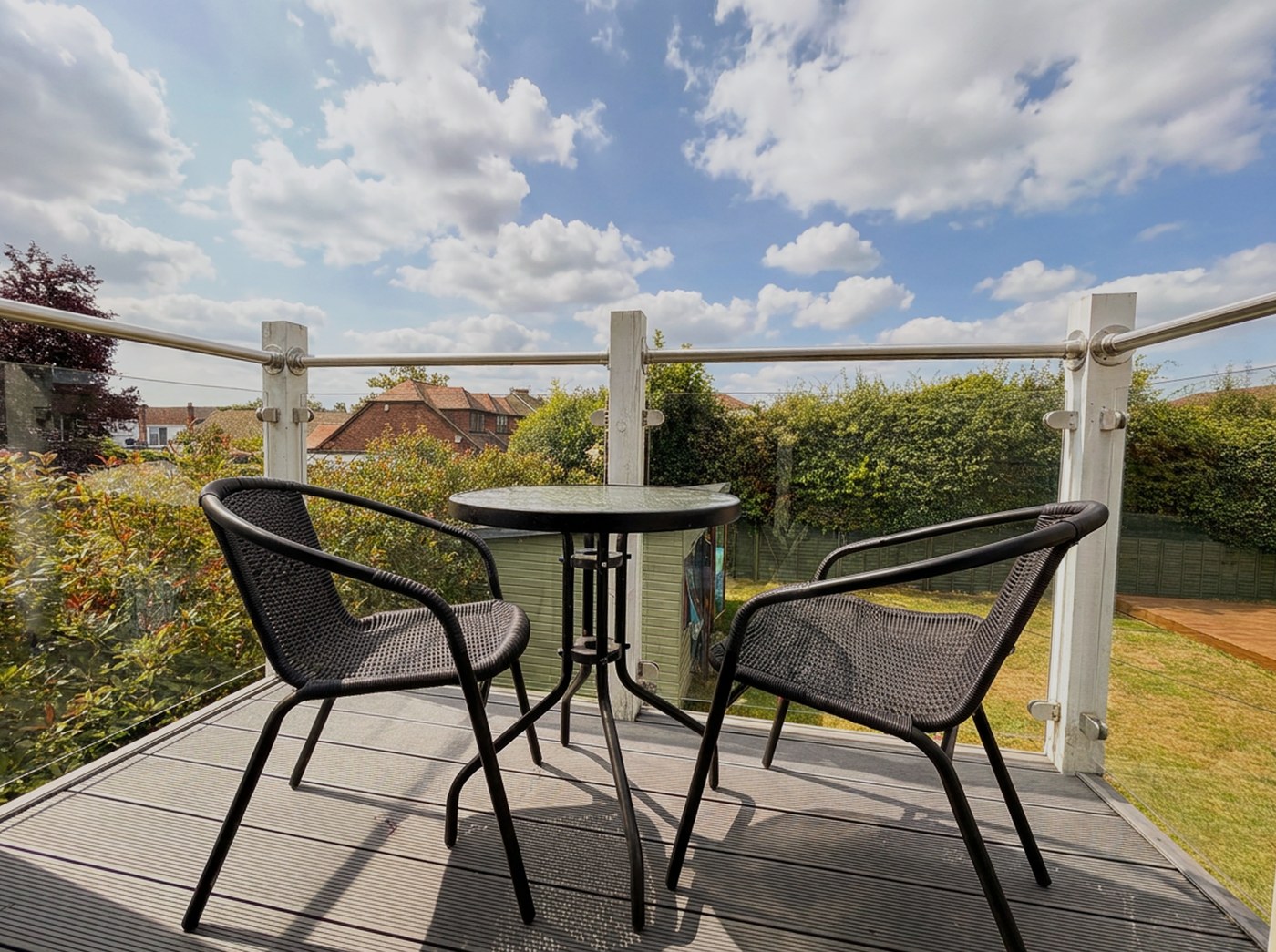 Balcony with a bistro table and chairs overlooking the garden.