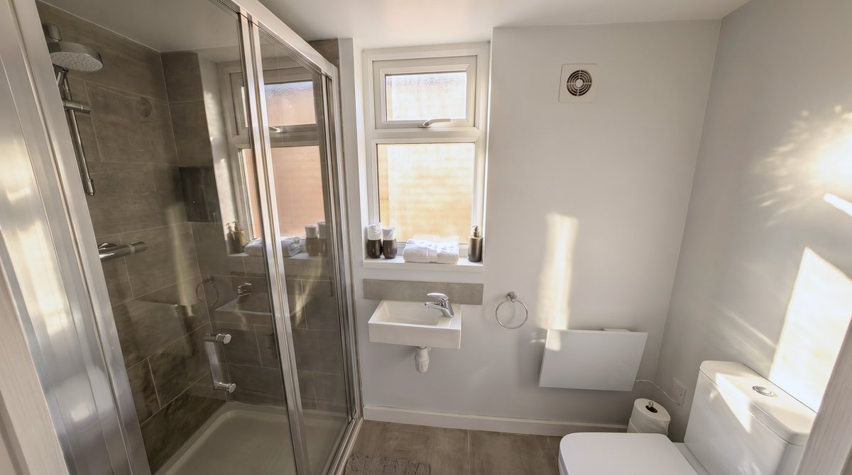 Walk-in shower, basin and window in the studio apartment shower room.
